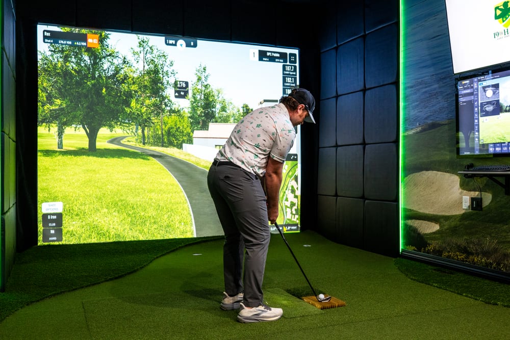 Golfer addressing the ball on the hitting mat of a custom golf simulator